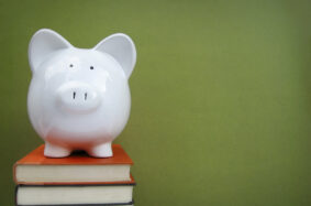 Piggy bank on top a a stack of books in front of green background