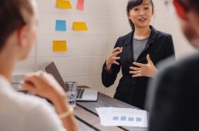 Asian female student in professional attire discussing with peers