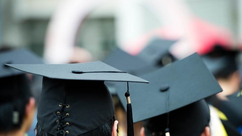 Back view of graduates wearing black caps and tassels