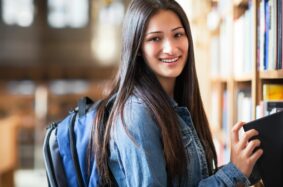 Latina student pulling book off a bookshelf