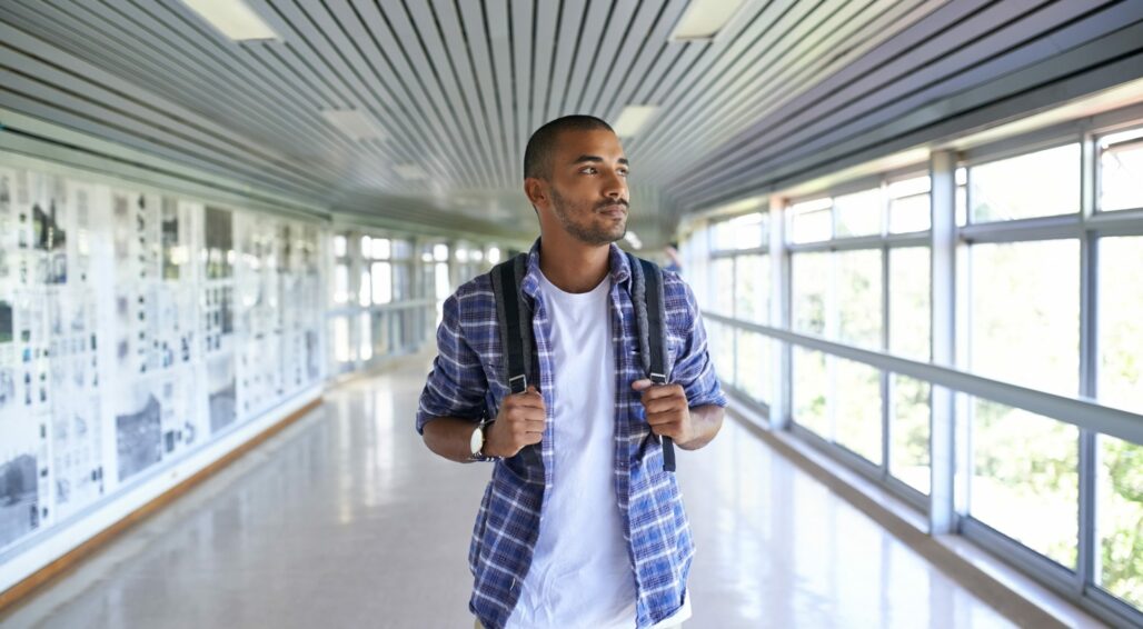 Male student walking in corridor staring out the window