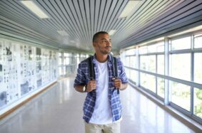 Male student walking in corridor staring out the window