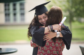 Female college graduate hugging her mom