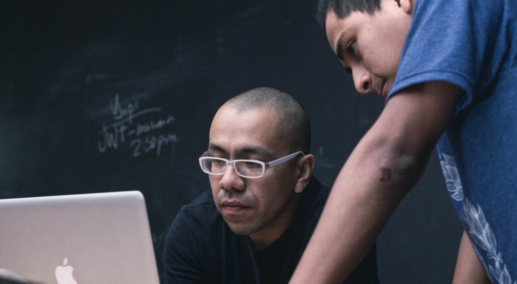 Professor and student working on laptop